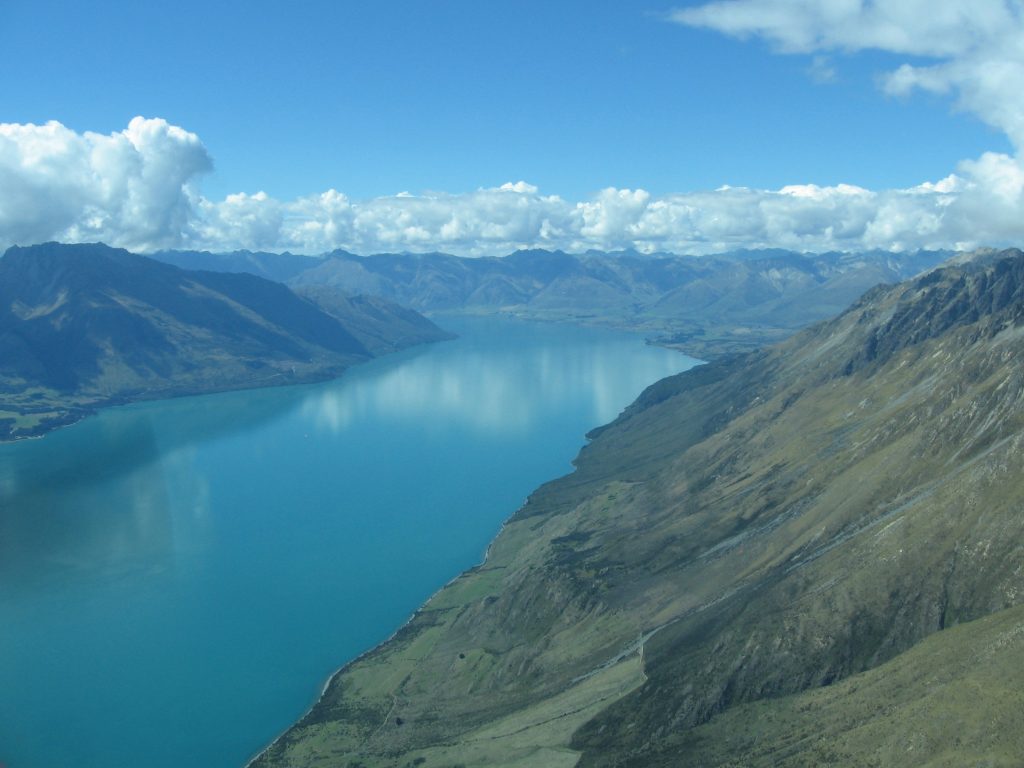 Fly over sparkling lakes nestled in the mountains on your way to Milford Sound